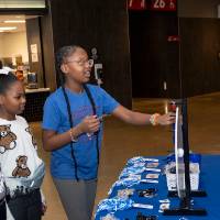 Group of three kids spinning prize wheel at merch table